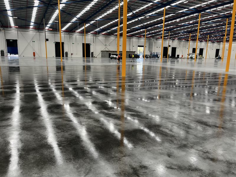 High-gloss sealed warehouse floor reflecting the roof lights