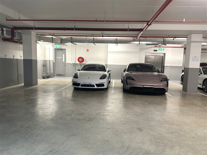 Two Porsches parked on a sealed, glossy service centre carpark floor