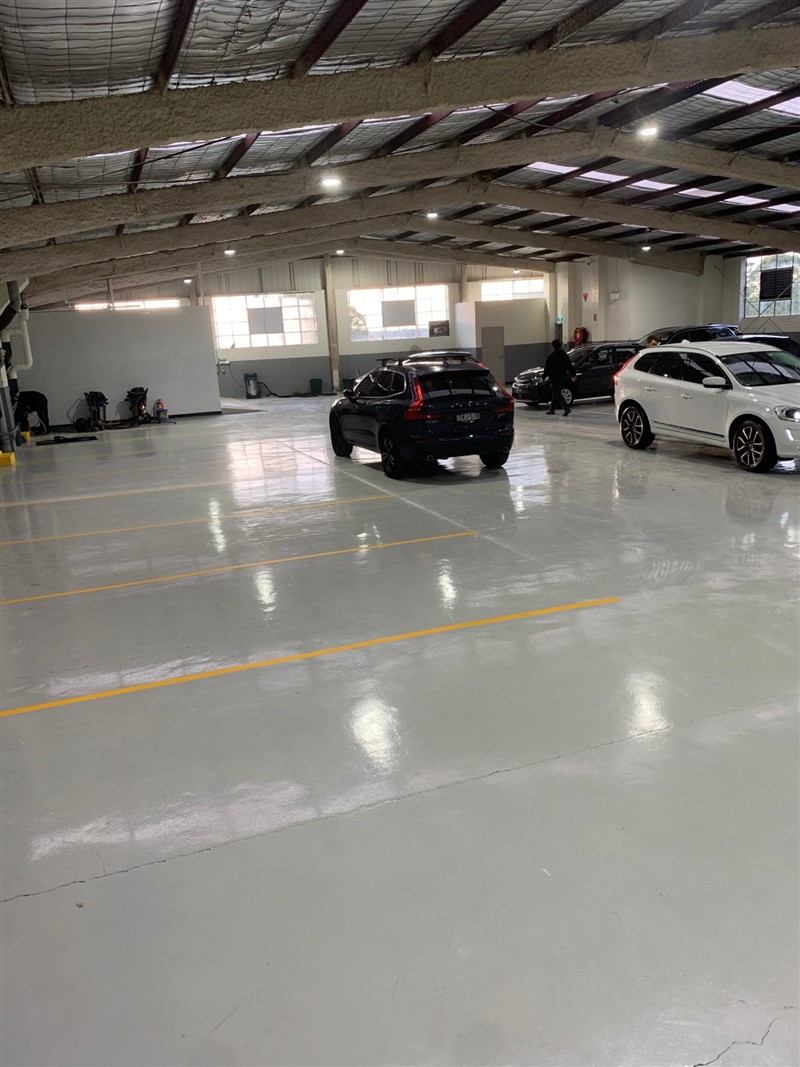 Glossy grey epoxy service floor with yellow bay lines and cars parked