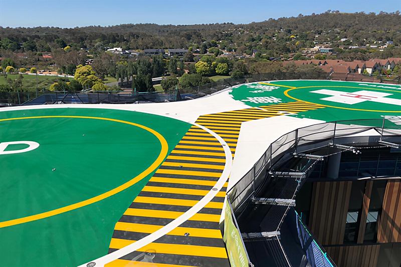 Two green helipads joined by a yellow and black hazard-striped walkway
