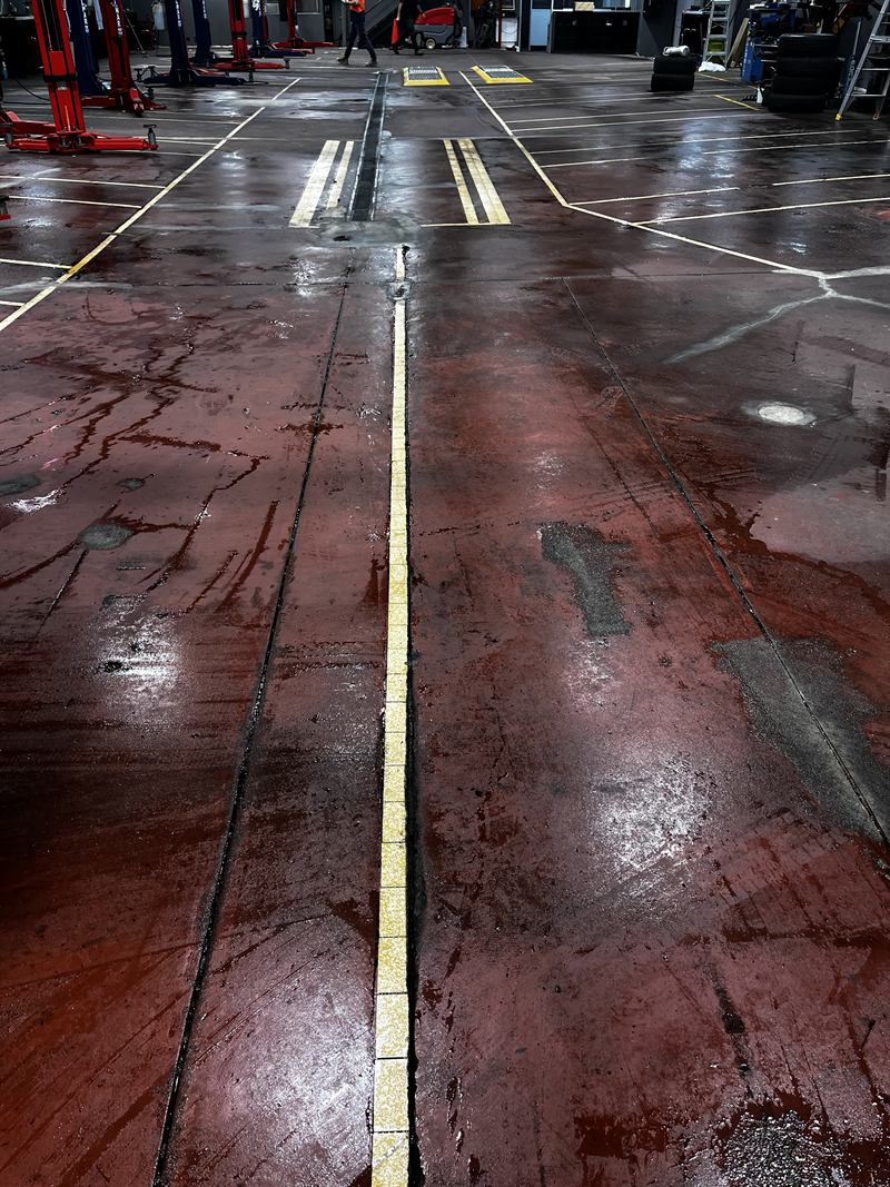 Workshop floor before: stained and worn red coating