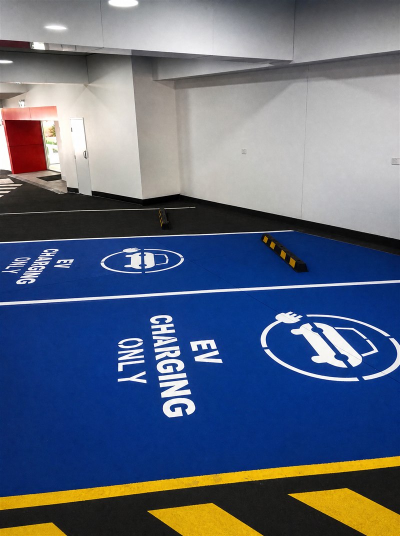 Blue EV charging bays with white stencils and a wheel stop in a basement carpark