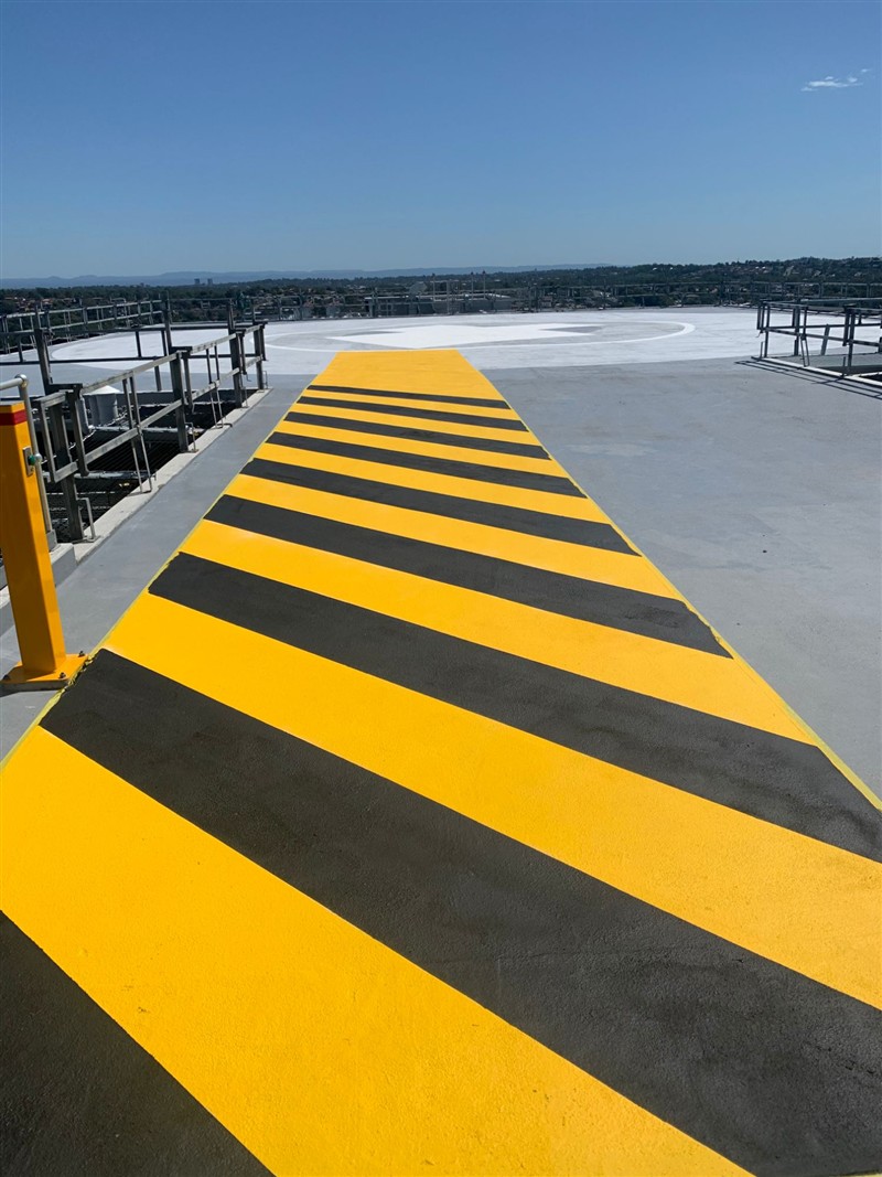 Yellow and black hazard-striped walkway leading onto a rooftop helipad